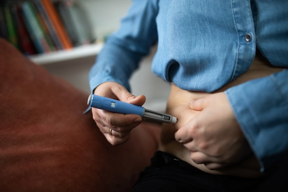 1 de 1 Pessoa aplicando insulina com um dispositivo semelhante a uma caneta, sentada. A imagem re...
