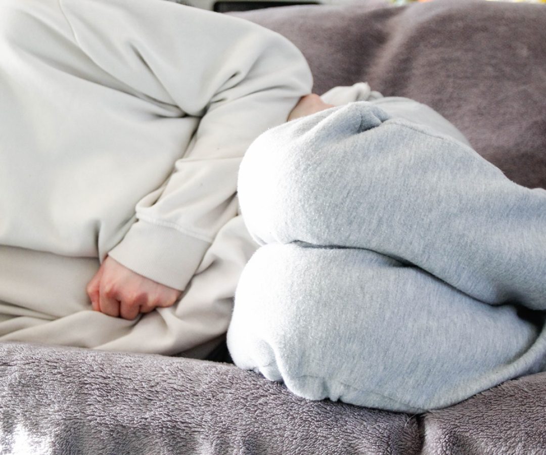 1 de 1 Mulher com pijama branco com cólica deitada em sofá - Metrópoles - Foto: Kinga Krzemins...
