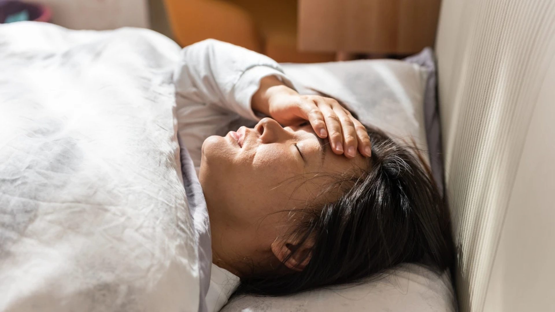 1 de 1 Jovem mulher asiática com a mão no rosto deitada em cama - Metrópoles - Foto: Getty Images
