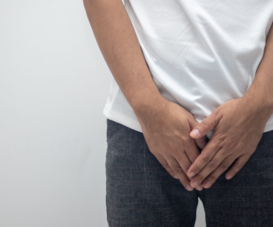 1 de 1 Imagem mostra homem com camiseta branca e calça preta com as mãos sobre as partes íntim...