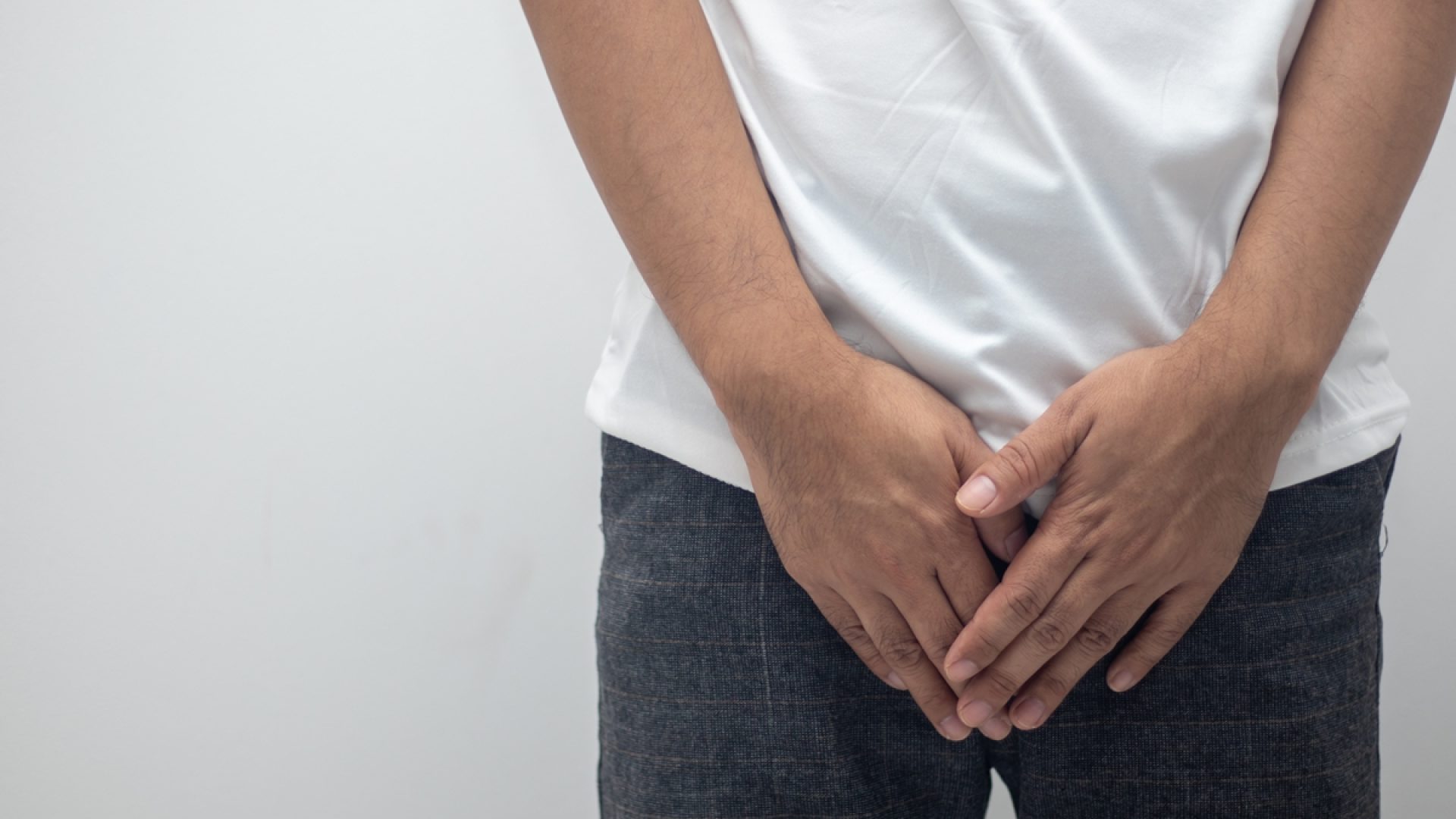 1 de 1 Imagem mostra homem com camiseta branca e calça preta com as mãos sobre as partes íntim...